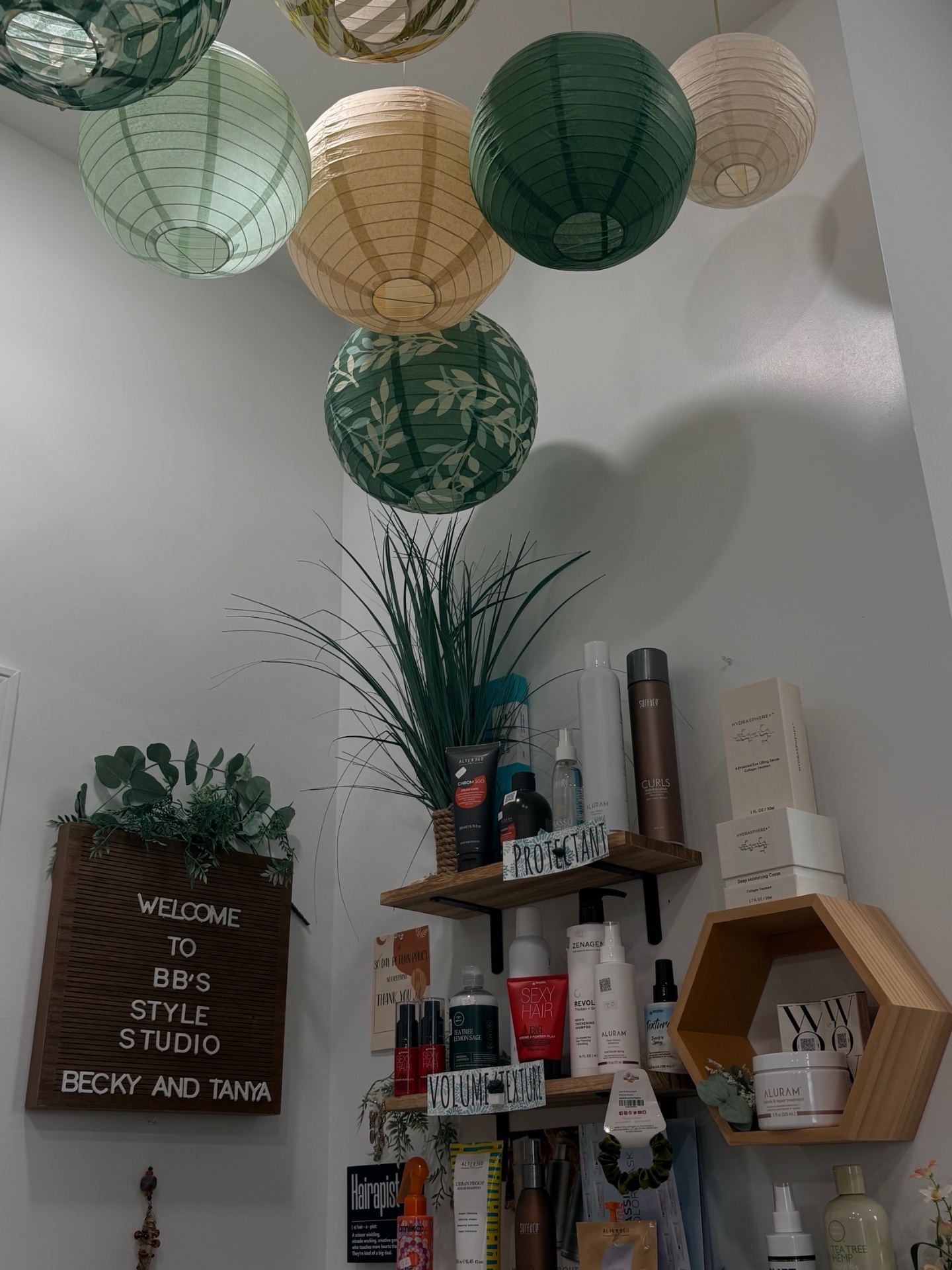 BBStyle Studio's product shelf with Surface, Alter Ego, and Aluram bottles beneath green and natural paper lanterns